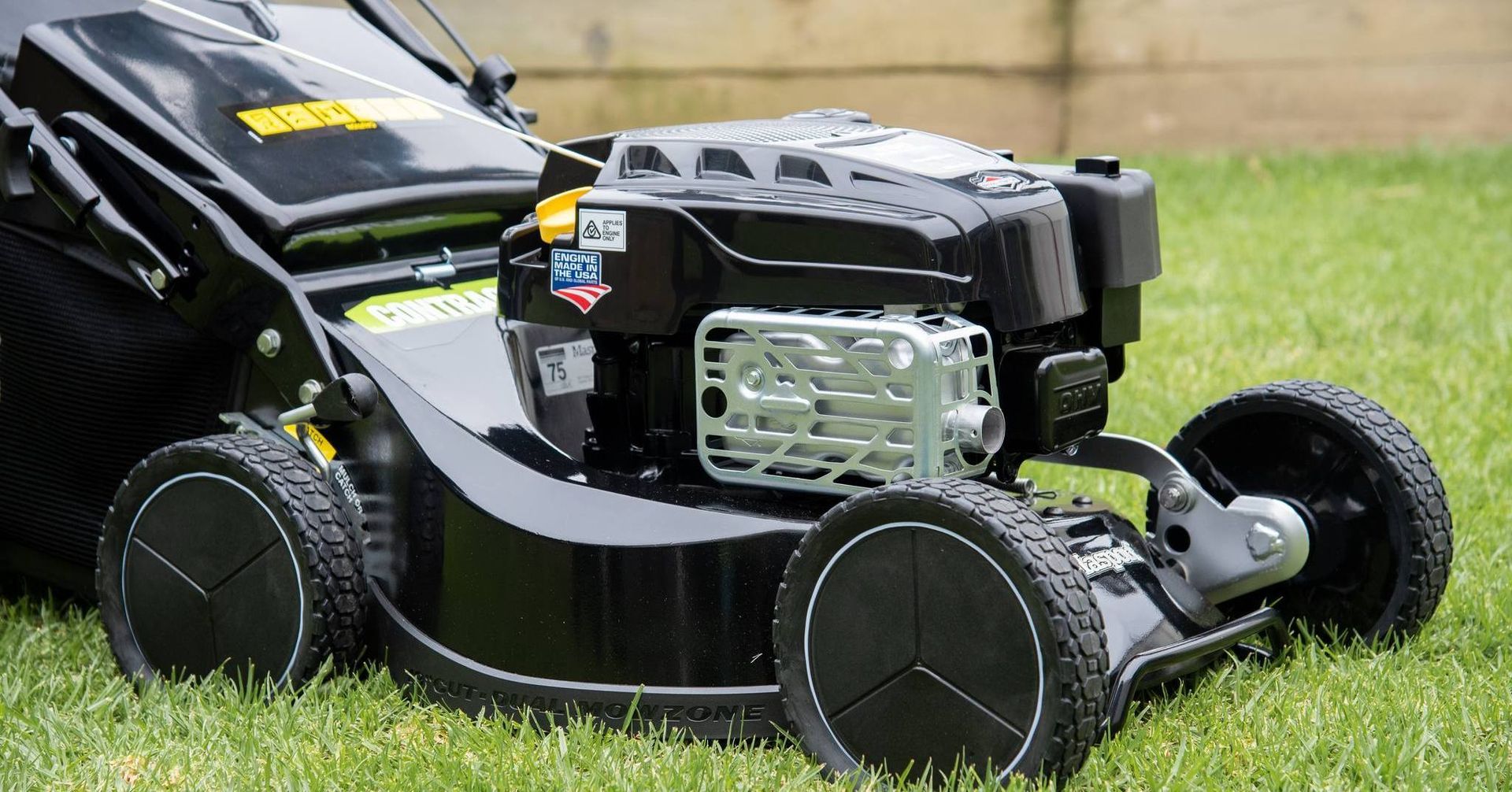 A Black Lawn Mower is Sitting on Top of a Lush Green Lawn — Stockers & Partridge In Paterson, NSW