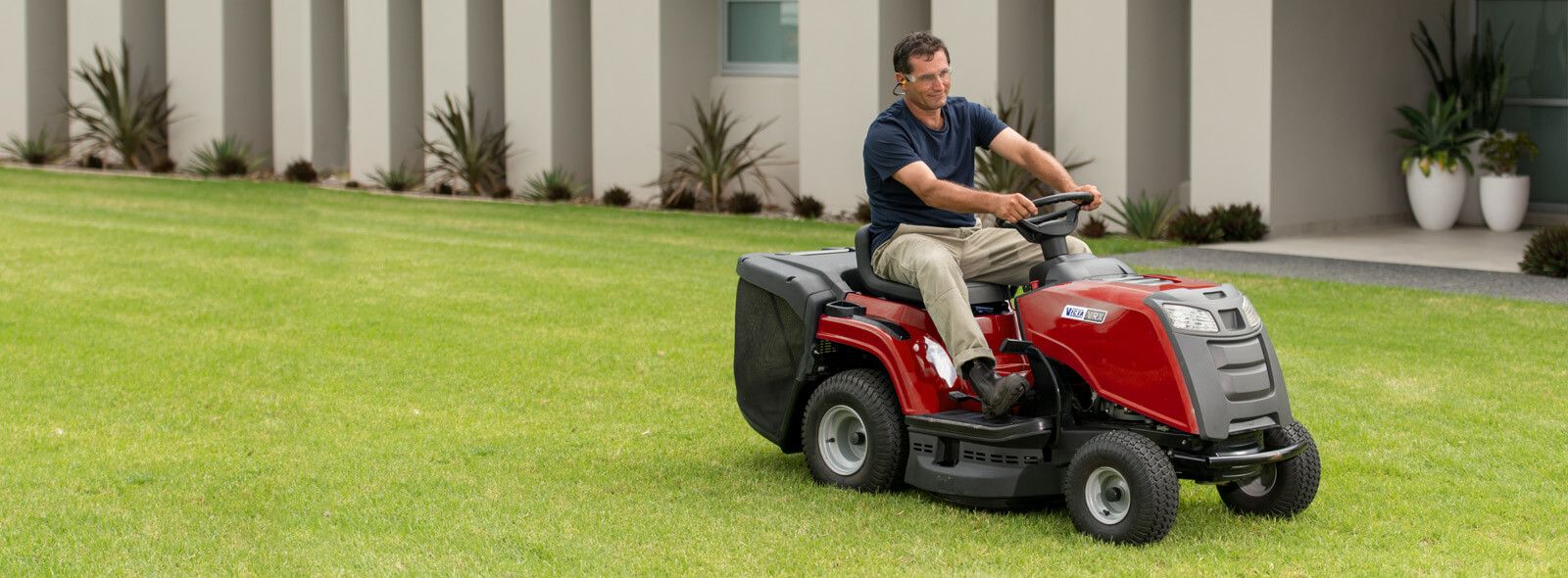 A Person is Mowing a Lush Green Lawn With a Lawn Mower — Stockers & Partridge In Paterson, NSW