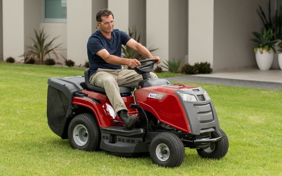 A Red Lawn Mower is Mowing a Lush Green Field — Stockers & Partridge In Dungog, NSW