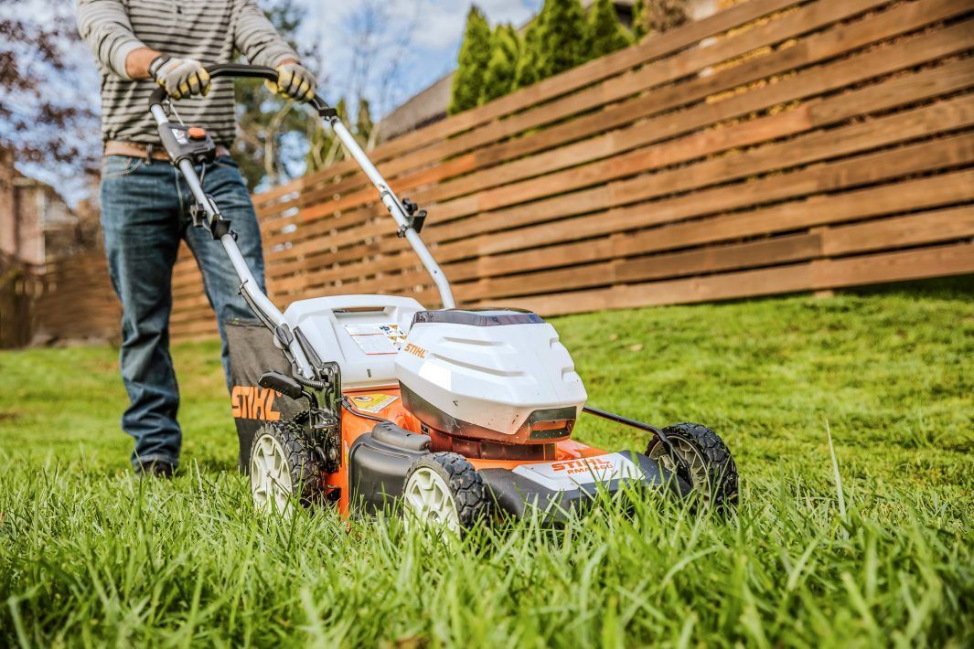 A Lawn Mower is Cutting a Lush Green Lawn in Front of a House — Stockers & Partridge In Paterson, NSW