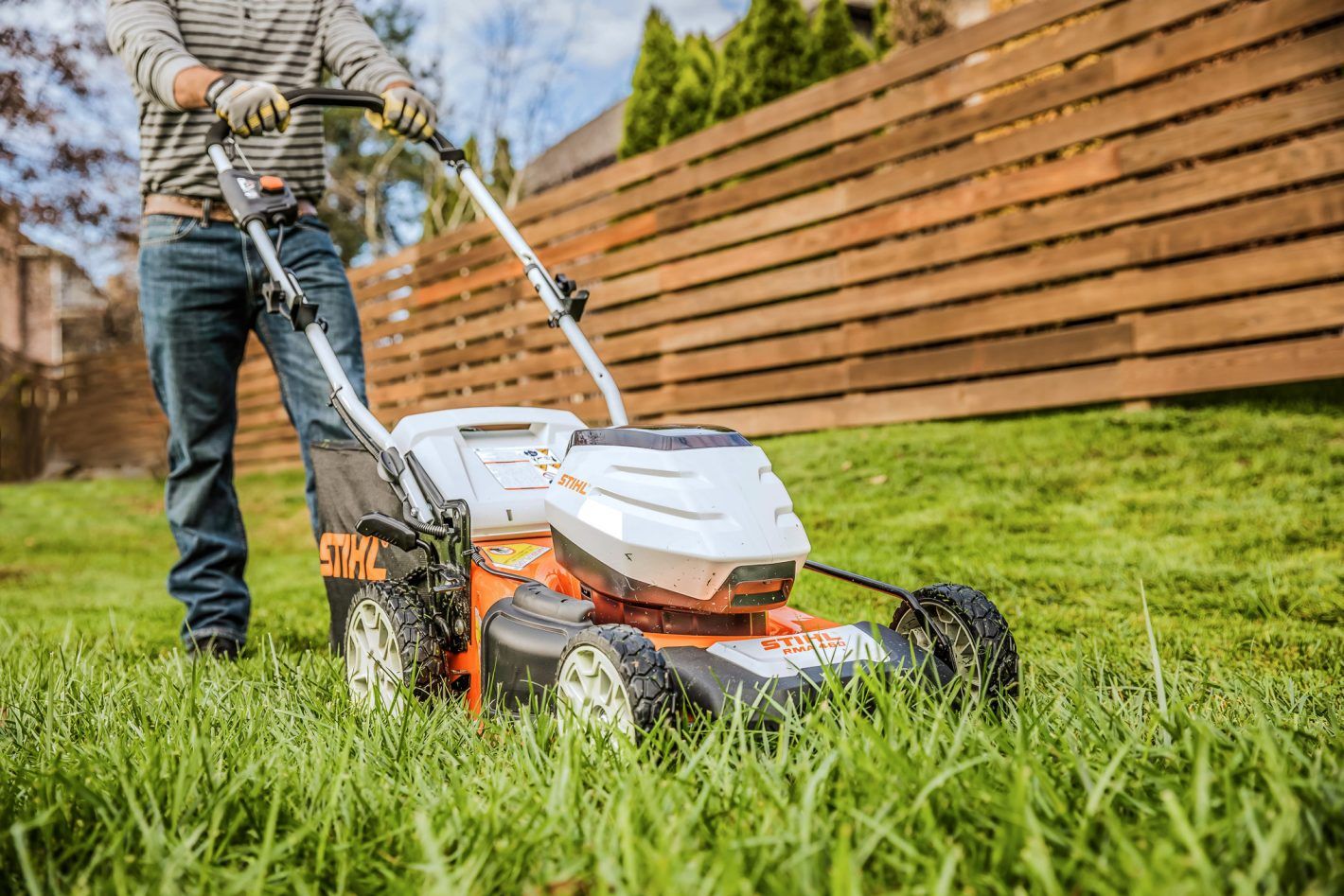 A Man is Cutting a Lush Green Lawn With a Lawn Mower — Stockers & Partridge In Paterson, NSW