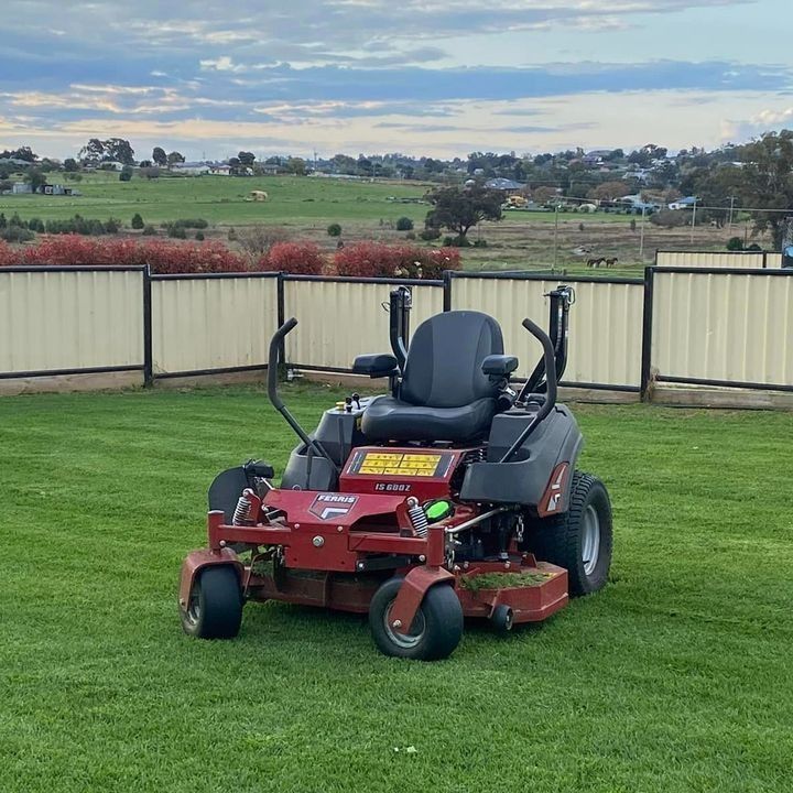 A Man is Riding a Red Lawn Mower in a Park — Stockers & Partridge In Paterson, NSW