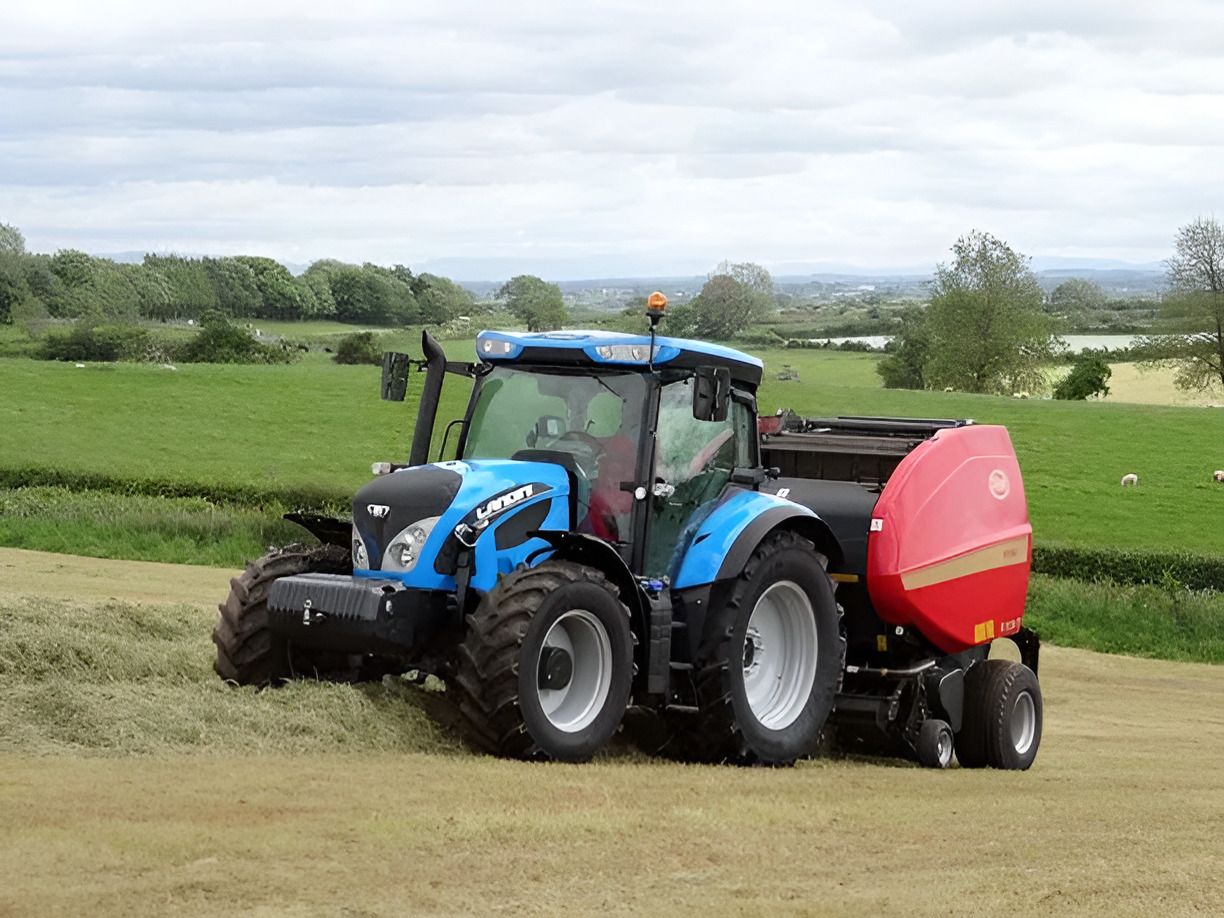 A Blue Tractor is Baling Hay in a Field  — Stockers & Partridge In Paterson, NSW