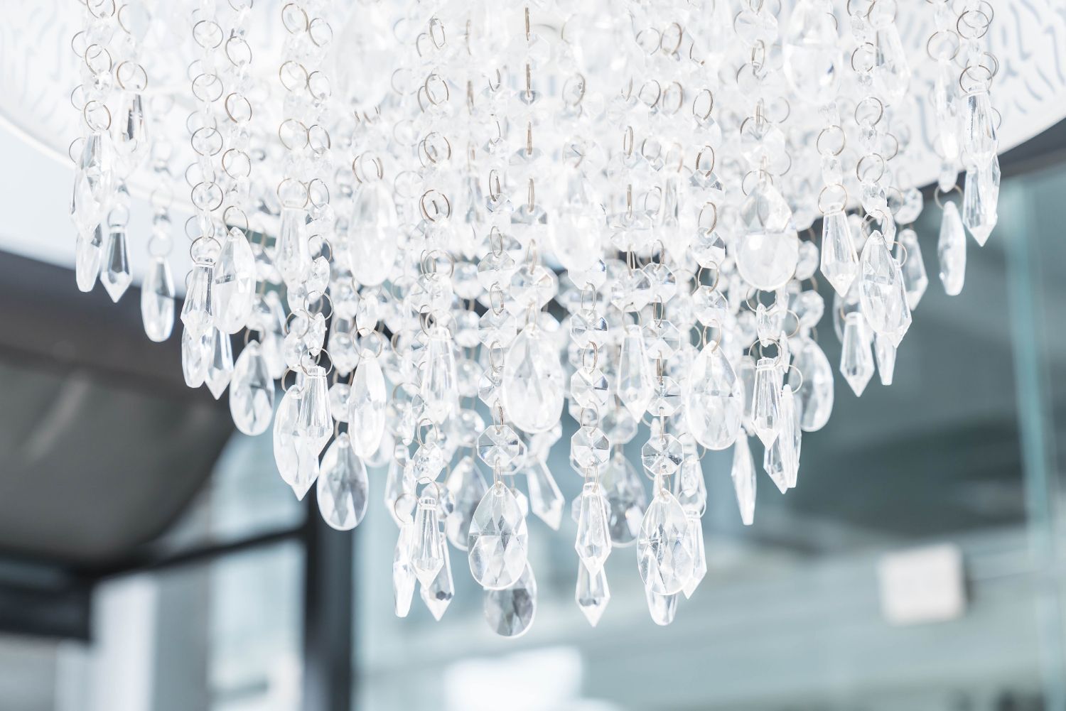 Close-up of a sparkling crystal chandelier hanging from the ceiling, reflecting light.