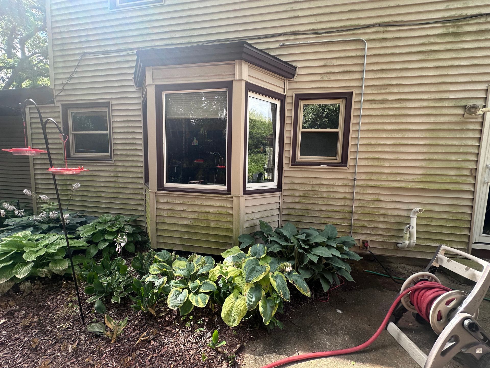 A house with a bay window and a hose in front of it.