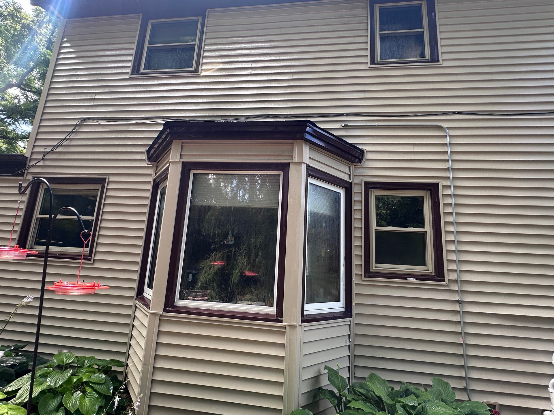 A house with a bay window and a bird feeder in front of it.