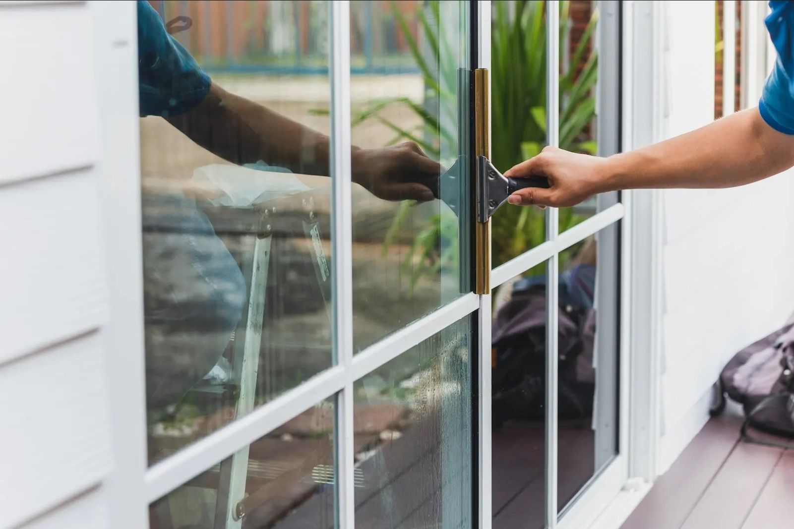 A man is opening a sliding glass door with a screwdriver.