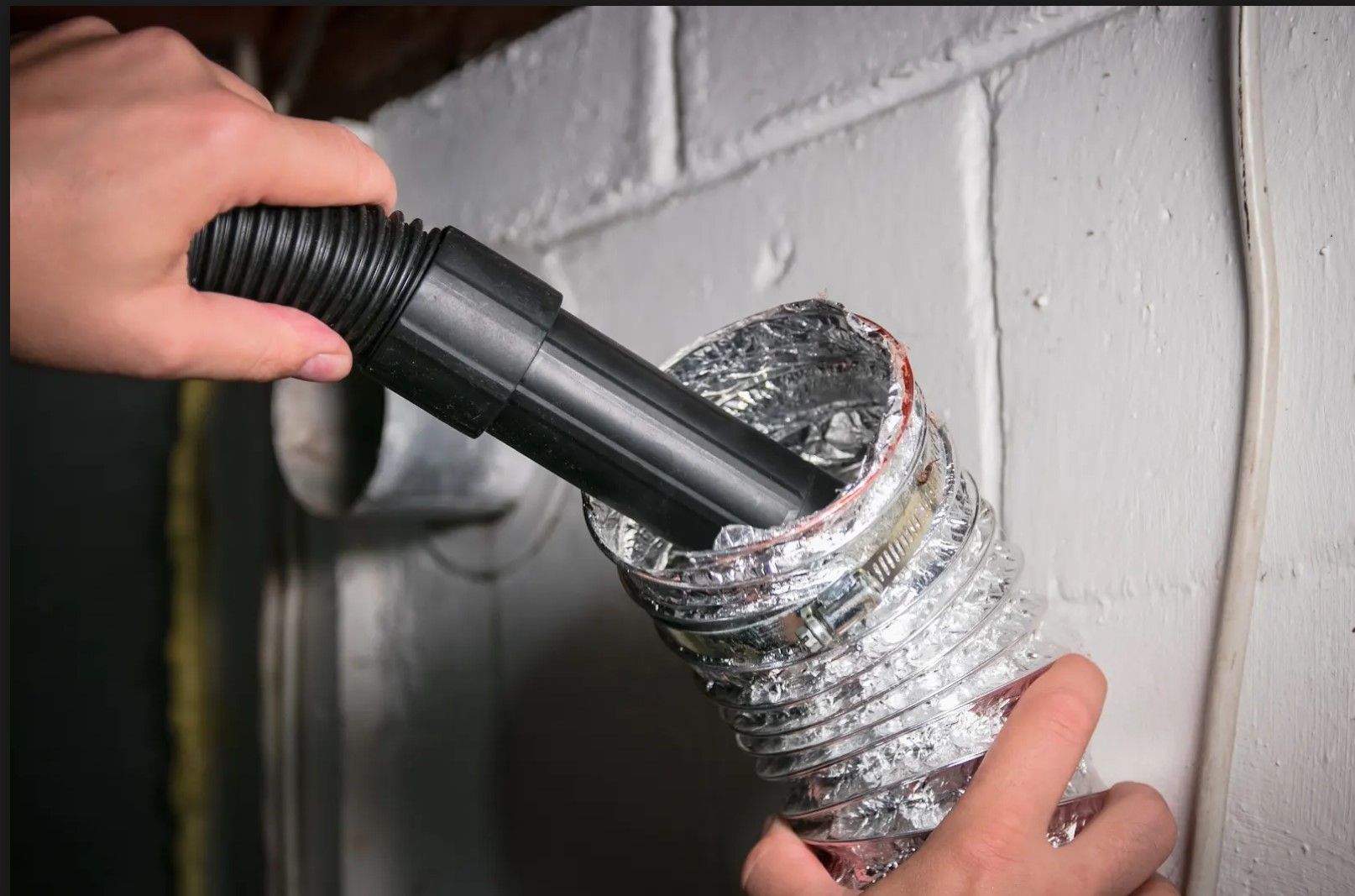 A person is using a vacuum cleaner to clean a duct.