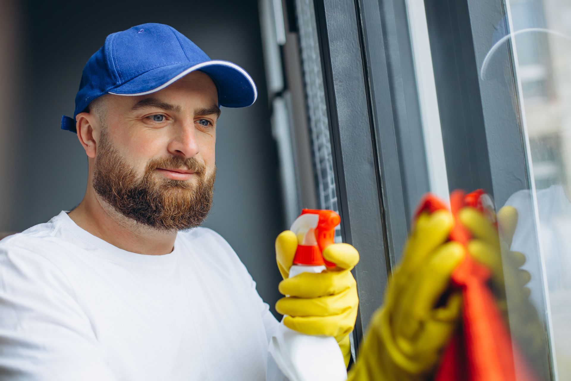 A man is cleaning a window with a spray bottle and a cloth.