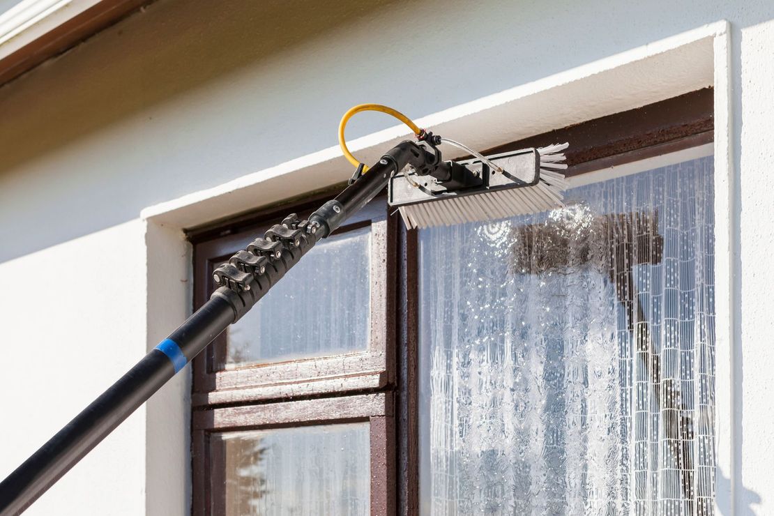 A person is cleaning a window with a brush.