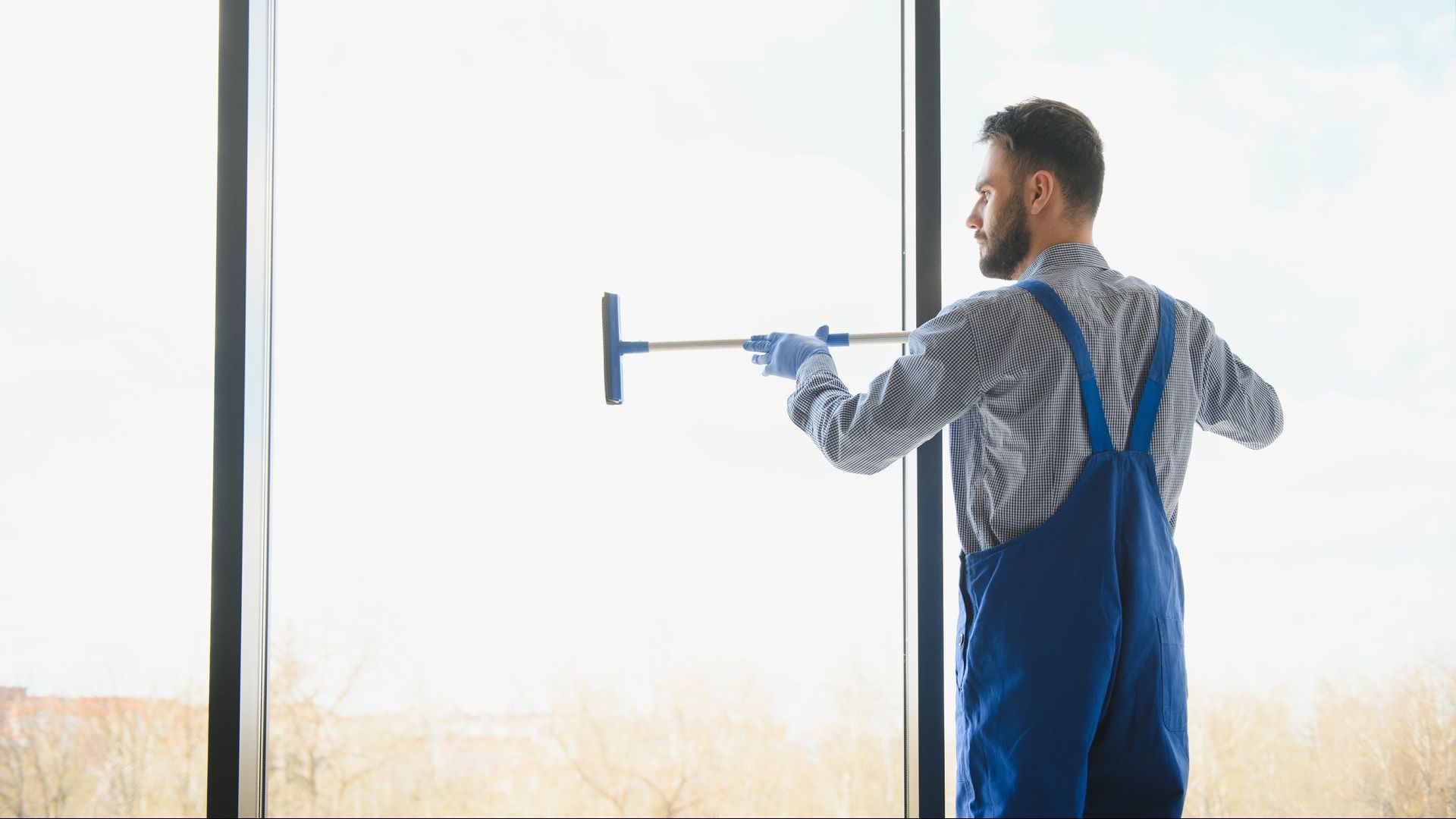 A man is cleaning a window with a squeegee.