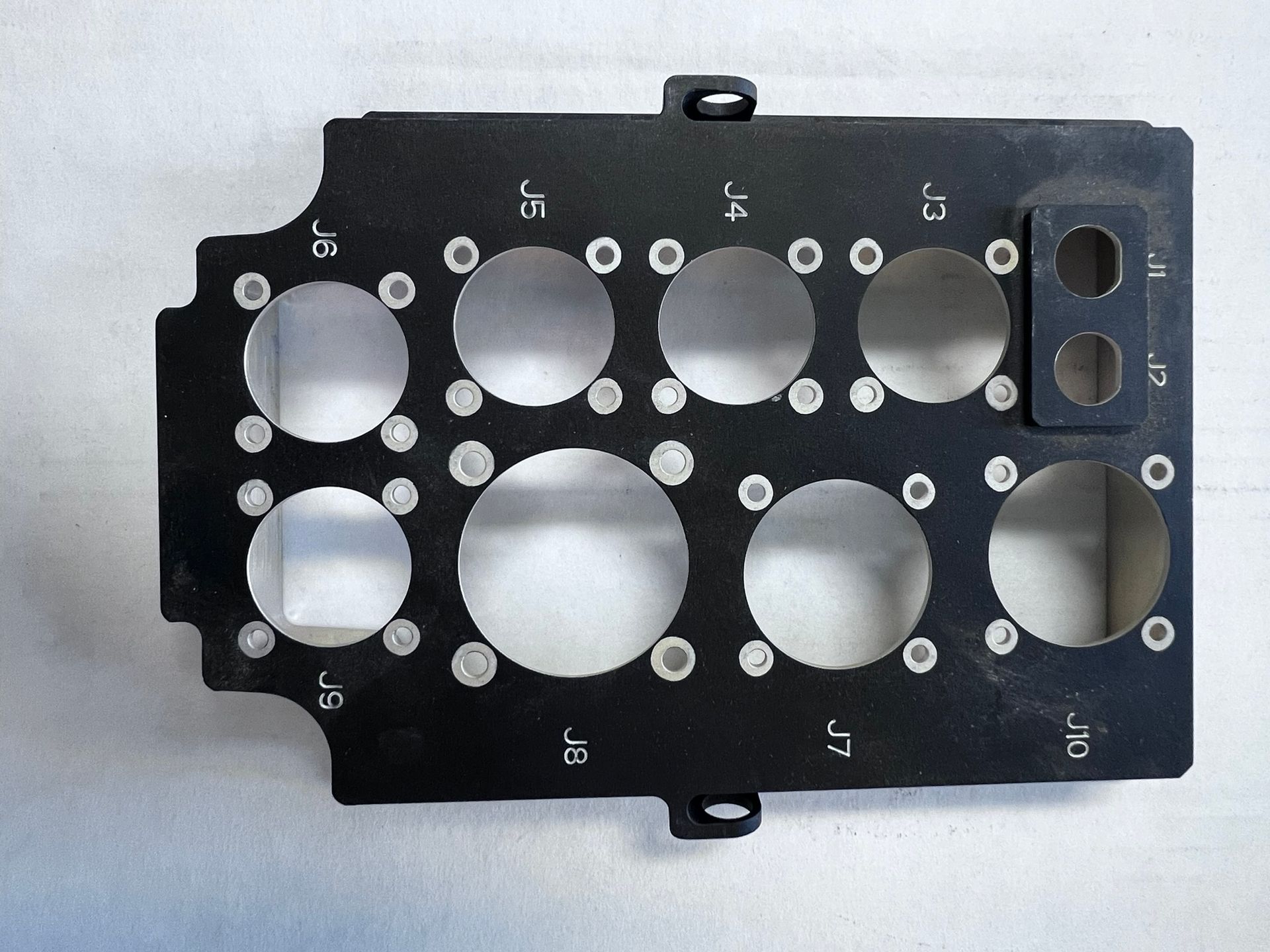 A black item with holes in it and the letters j and k on it