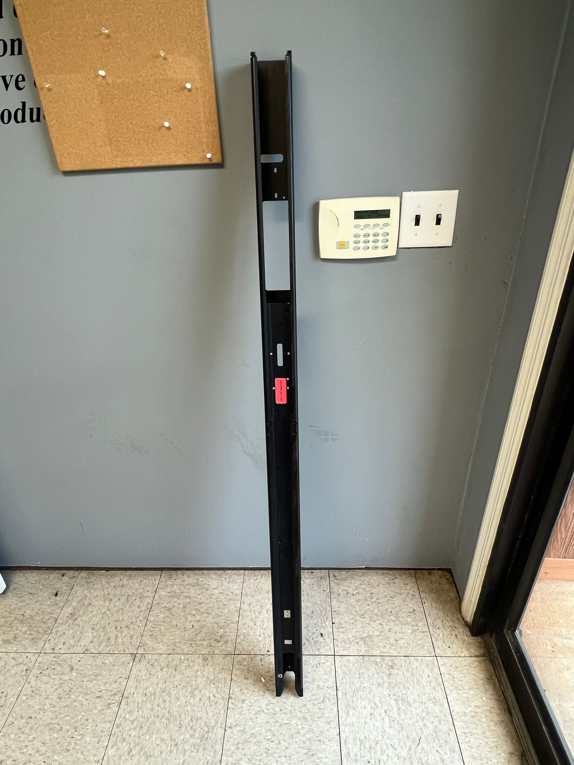 A long piece of metal is sitting on the floor next to a door