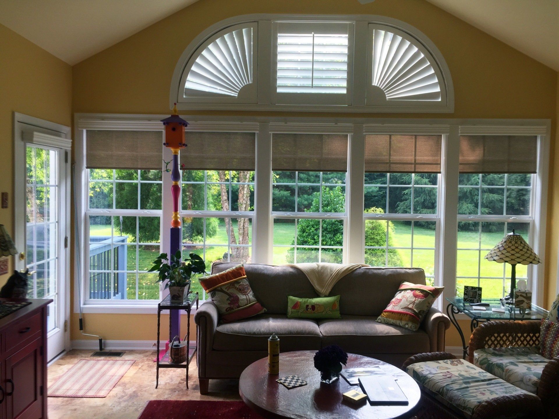 Arched plantation shutters above solar shades