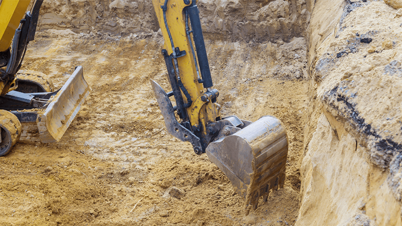 Rock hammer attachment breaking large boulders on job site