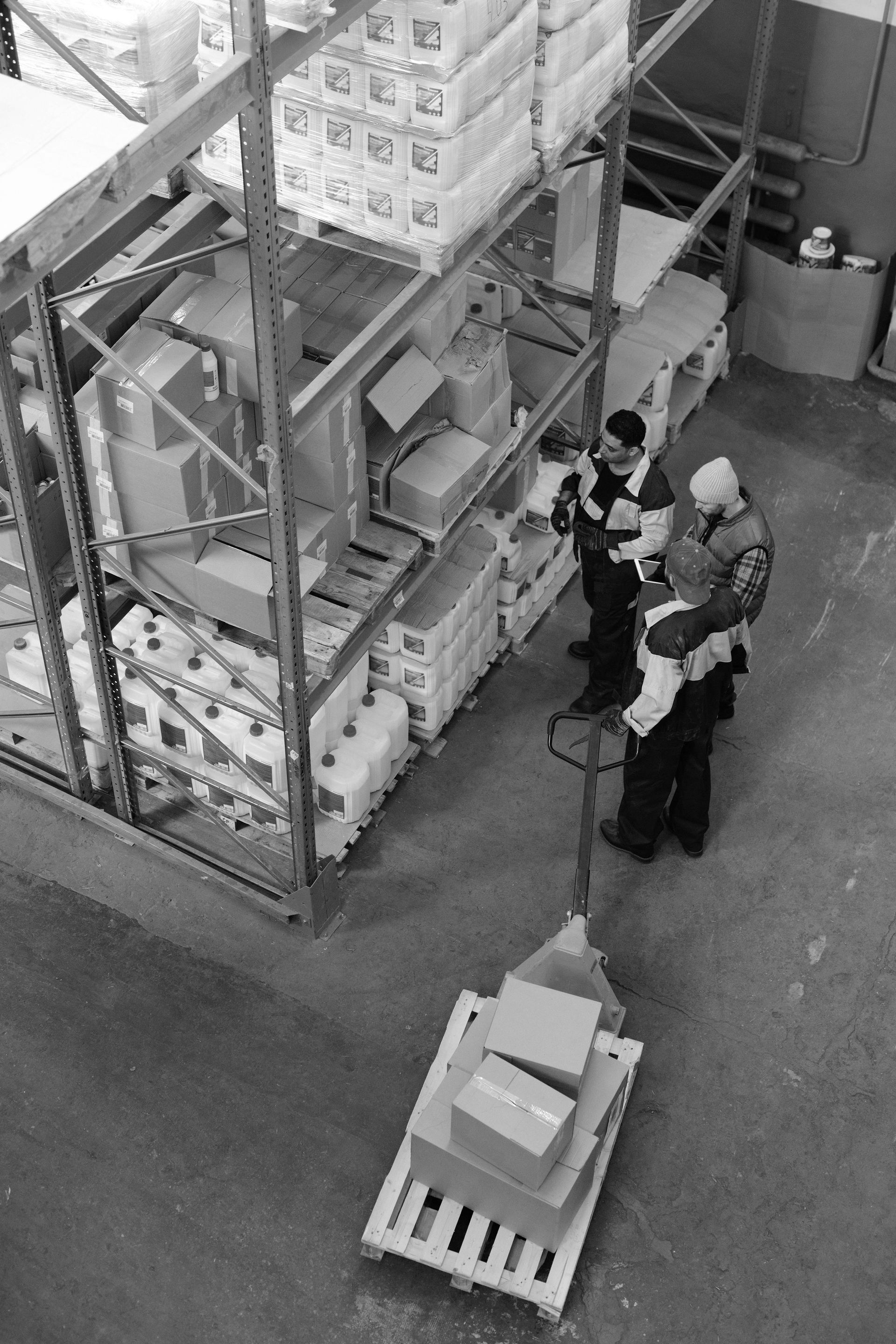 A group of people are standing in a warehouse looking at boxes on a pallet.