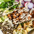 A close up of a salad with chickpeas , cauliflower , quinoa , radishes and avocado.