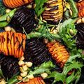 A close up of a salad with vegetables and nuts on a plate.