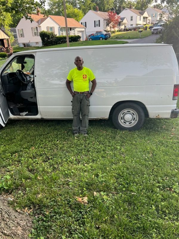 A man in a yellow shirt is standing next to a white van.
