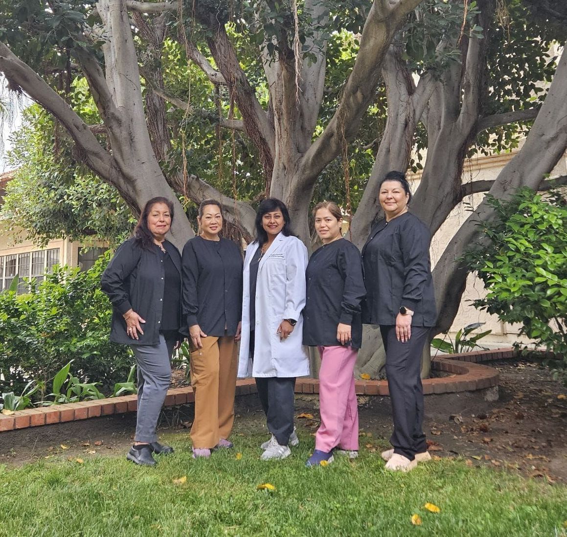 A group of women are posing for a picture in front of a tree.