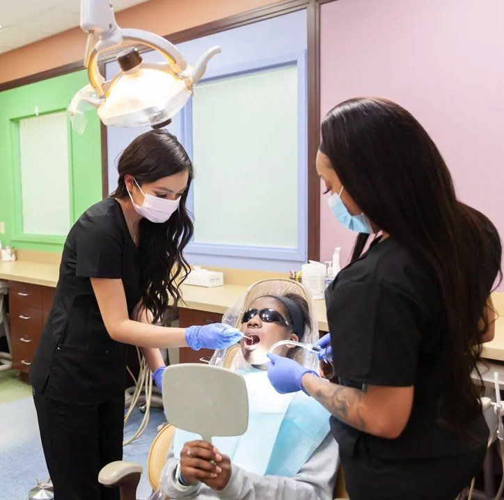 A woman in a dental chair is looking at her teeth in a mirror
