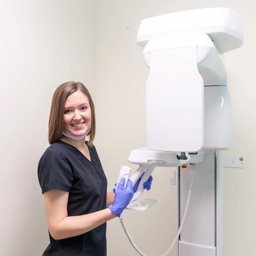 A woman is standing in front of an x-ray machine.