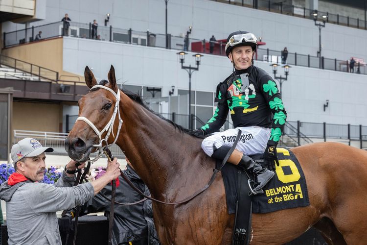 Horse race with three jockeys and galloping horses kicking up dirt at the finish line