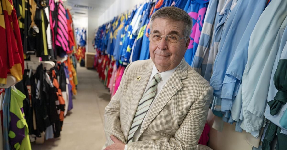 Terry Meyocks, CEO and President, stands in a room with rows of colorful horse racing jockey silks hanging on walls.