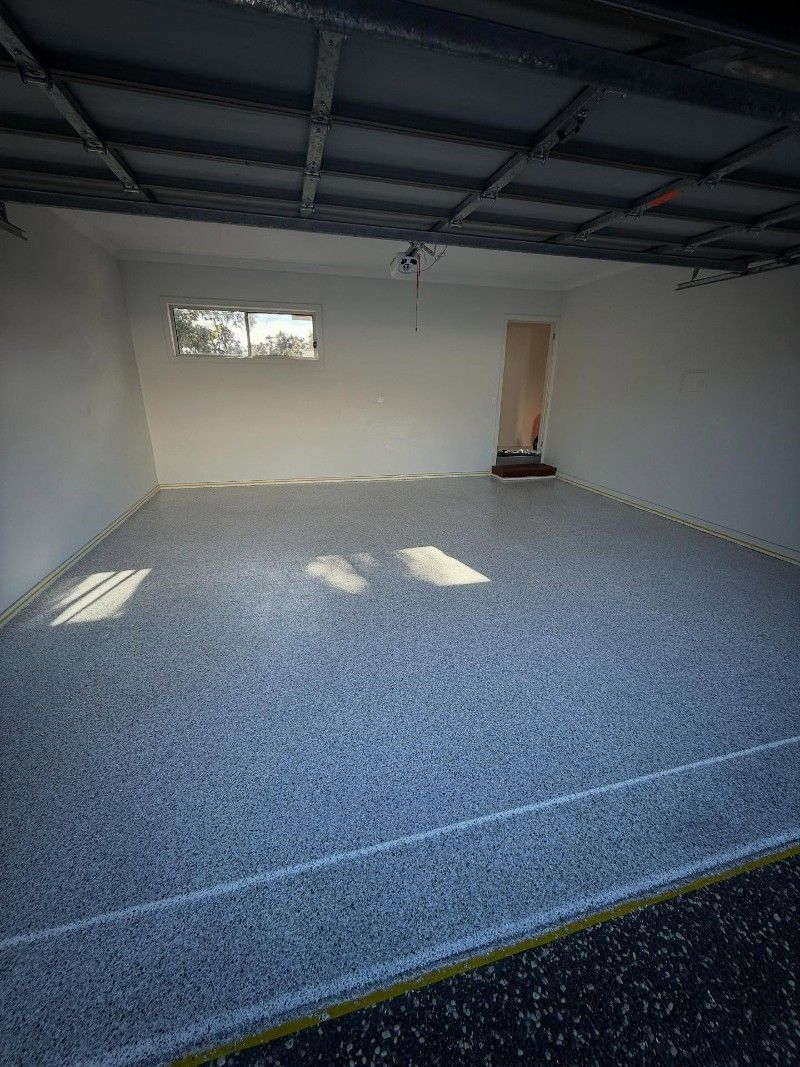 An Empty Garage With a Gray Floor and White Walls — Premier Epoxy Flooring Wollongong in Wollongong, NSW