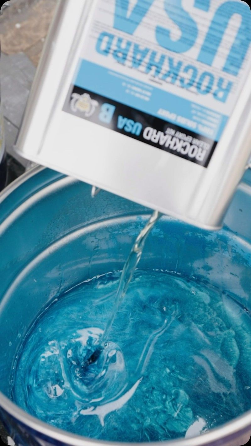 A Can of Rockhard is Poured Into a Bucket of Blue Liquid — Premier Epoxy Flooring Wollongong in Wollongong, NSW