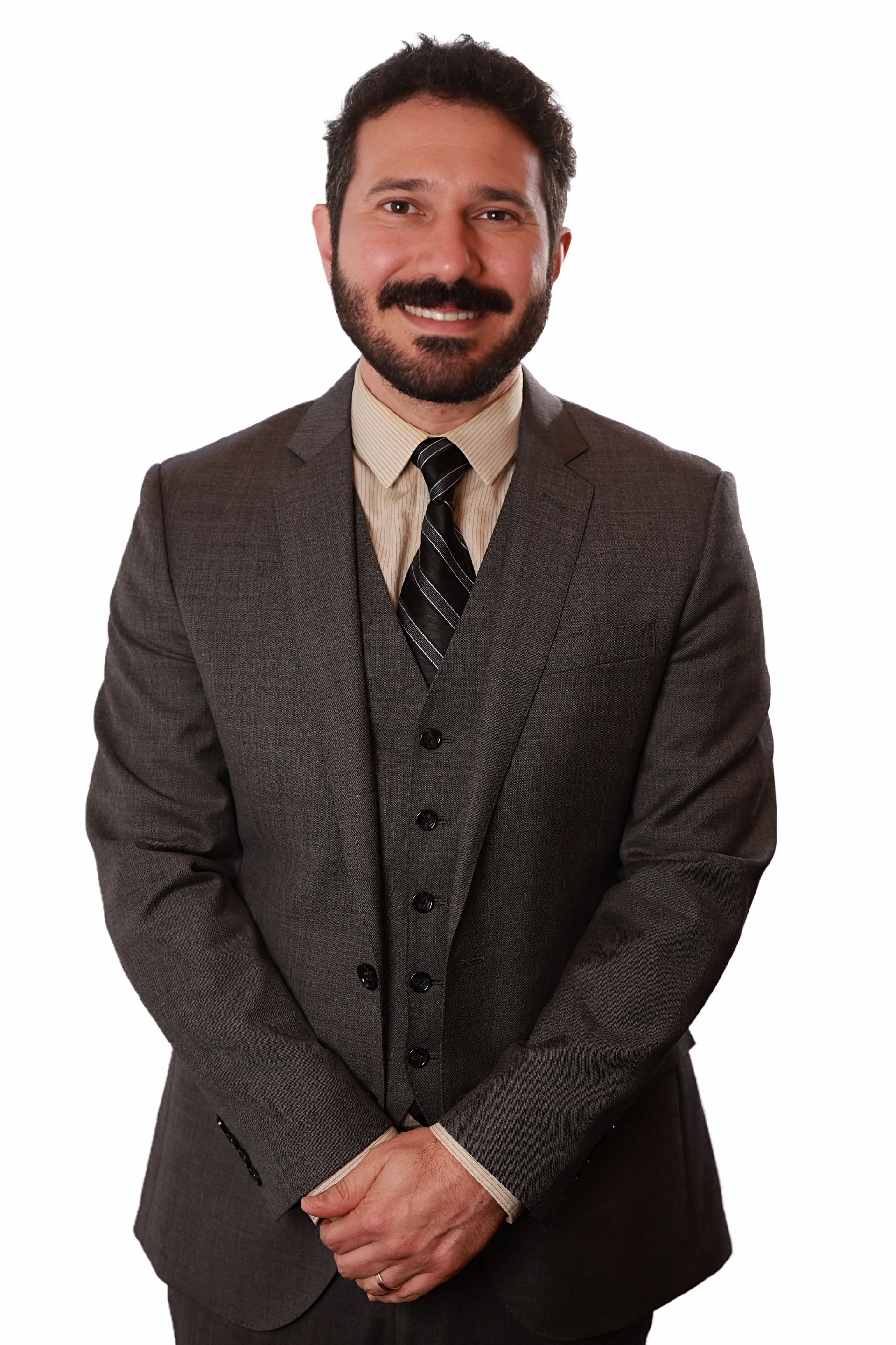 Man in gray suit and tie, hands clasped, smiling.
