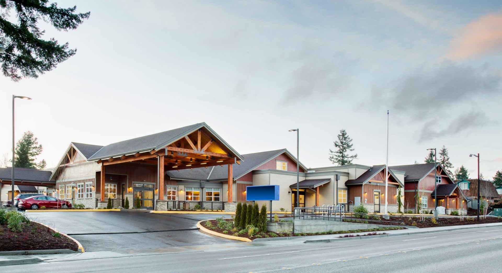 Modern healthcare facility with a covered entrance, wood accents, and a blue sign.