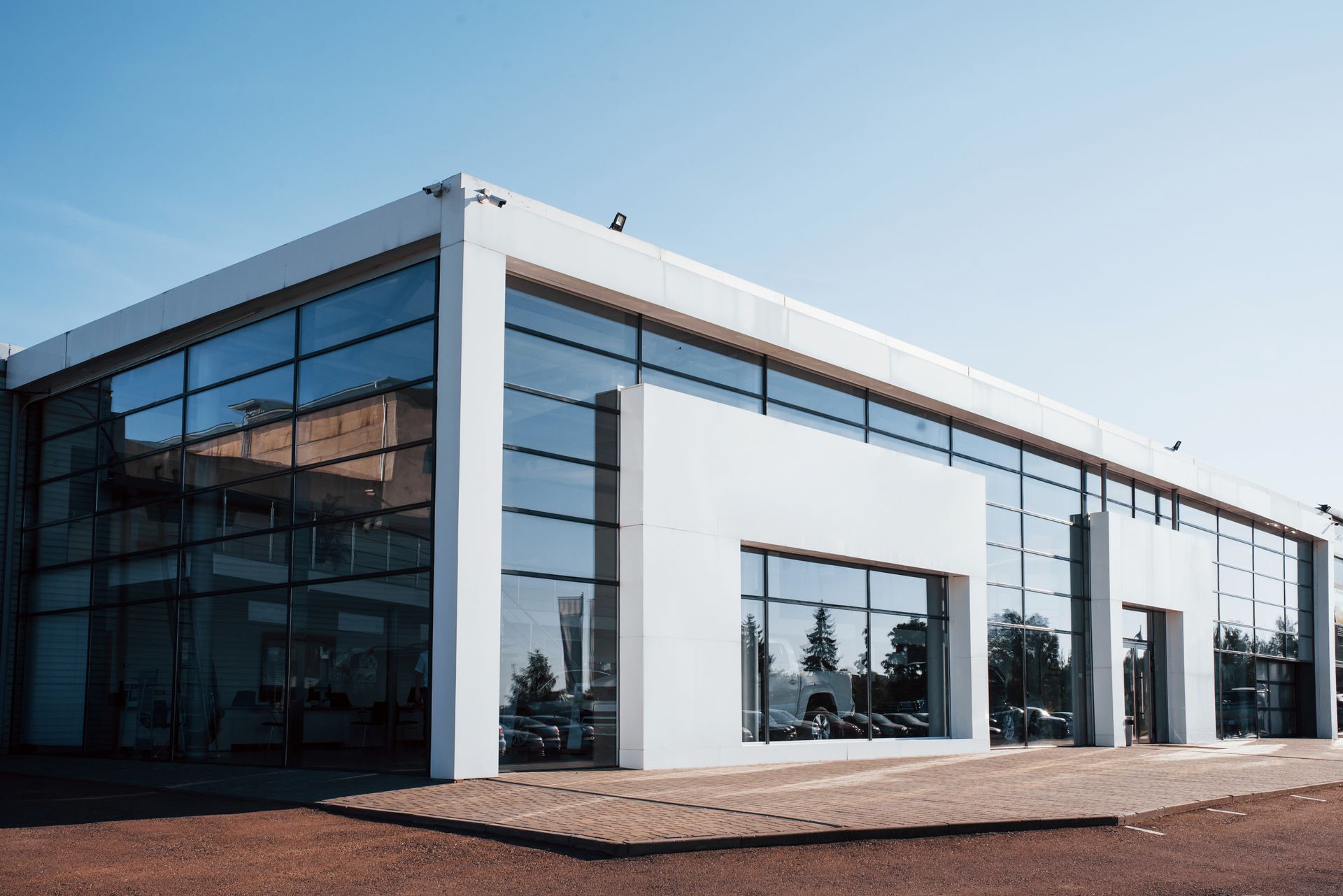 Modern white building with large glass windows under a clear blue sky.