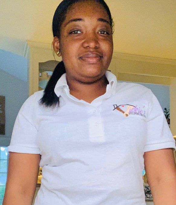 Woman wearing a white polo shirt with a logo, smiling in a well-lit indoor space.