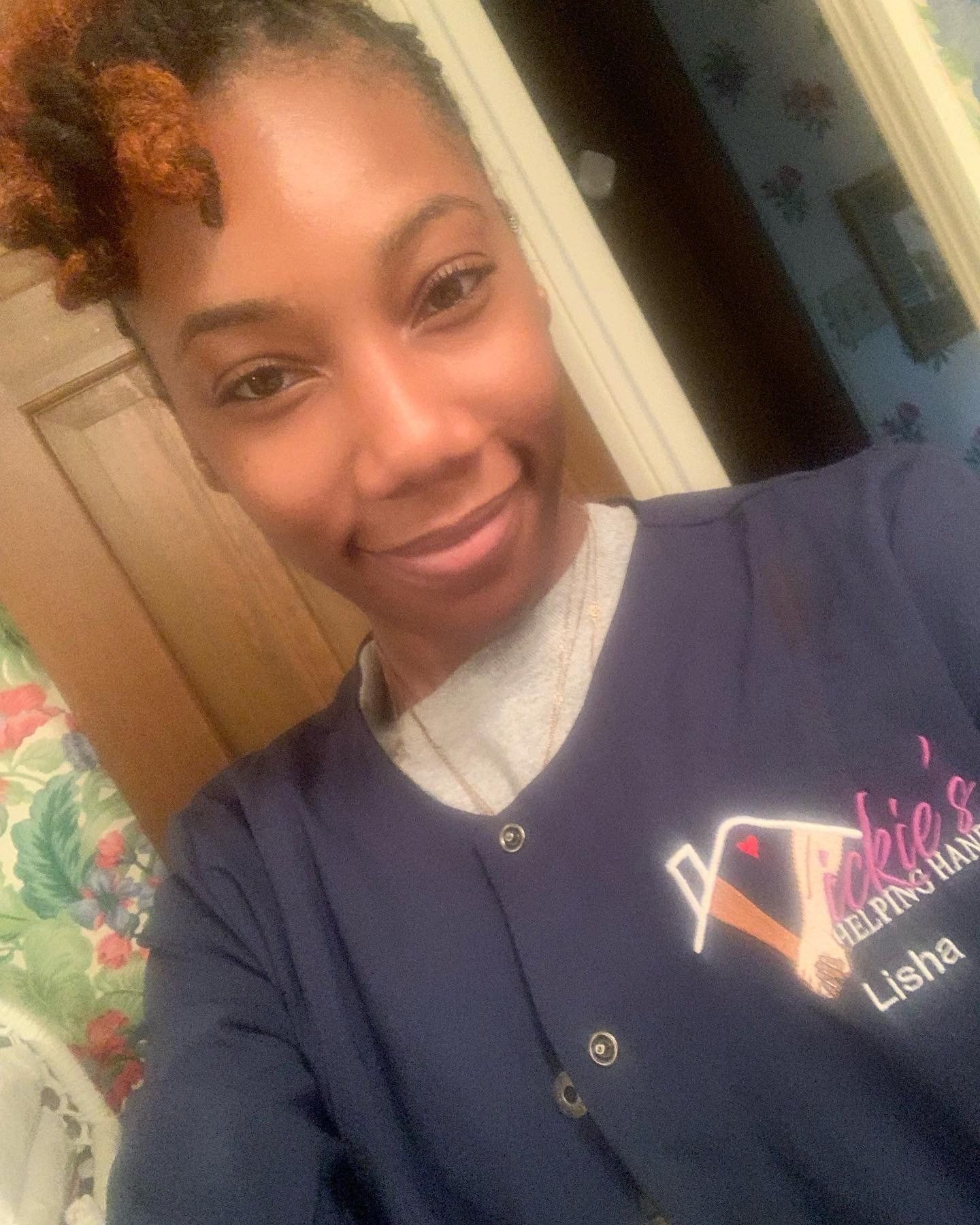 Woman in a dark blue uniform smiles in a bathroom, with text logo.