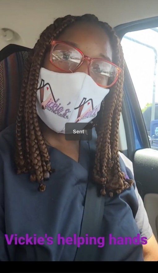 Person wearing a mask and glasses, inside a vehicle. Mask reads 