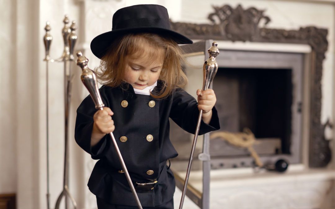 Child in chimney sweep costume holding tools near a fireplace.