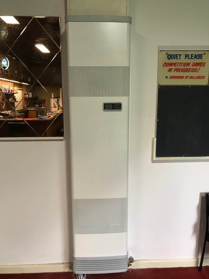 Tall white and gray air conditioning unit against a wall, a mirror and chalkboard are adjacent to it.