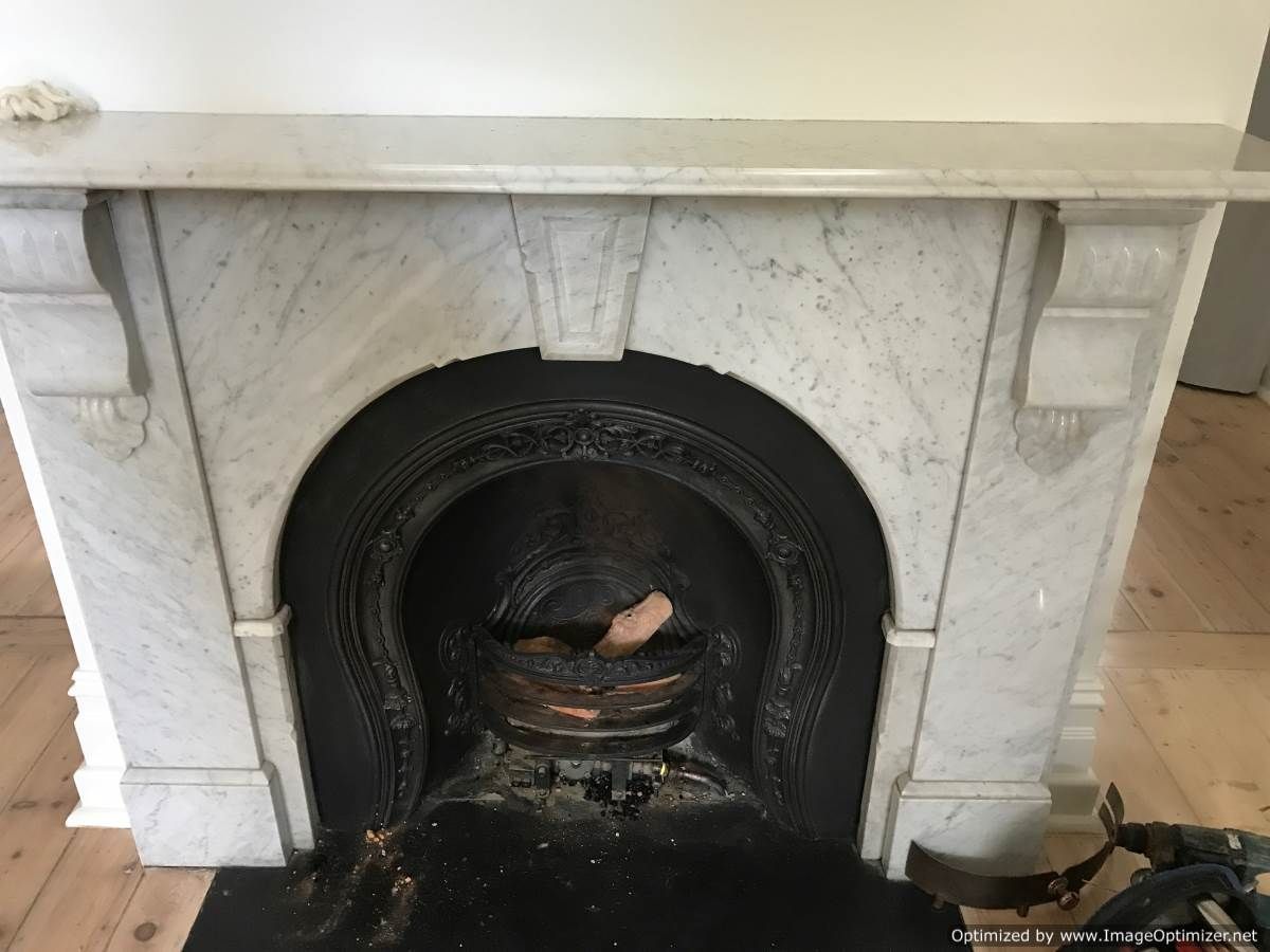 Marble fireplace with black interior. Fireplace has a decorative arch and mantel.
