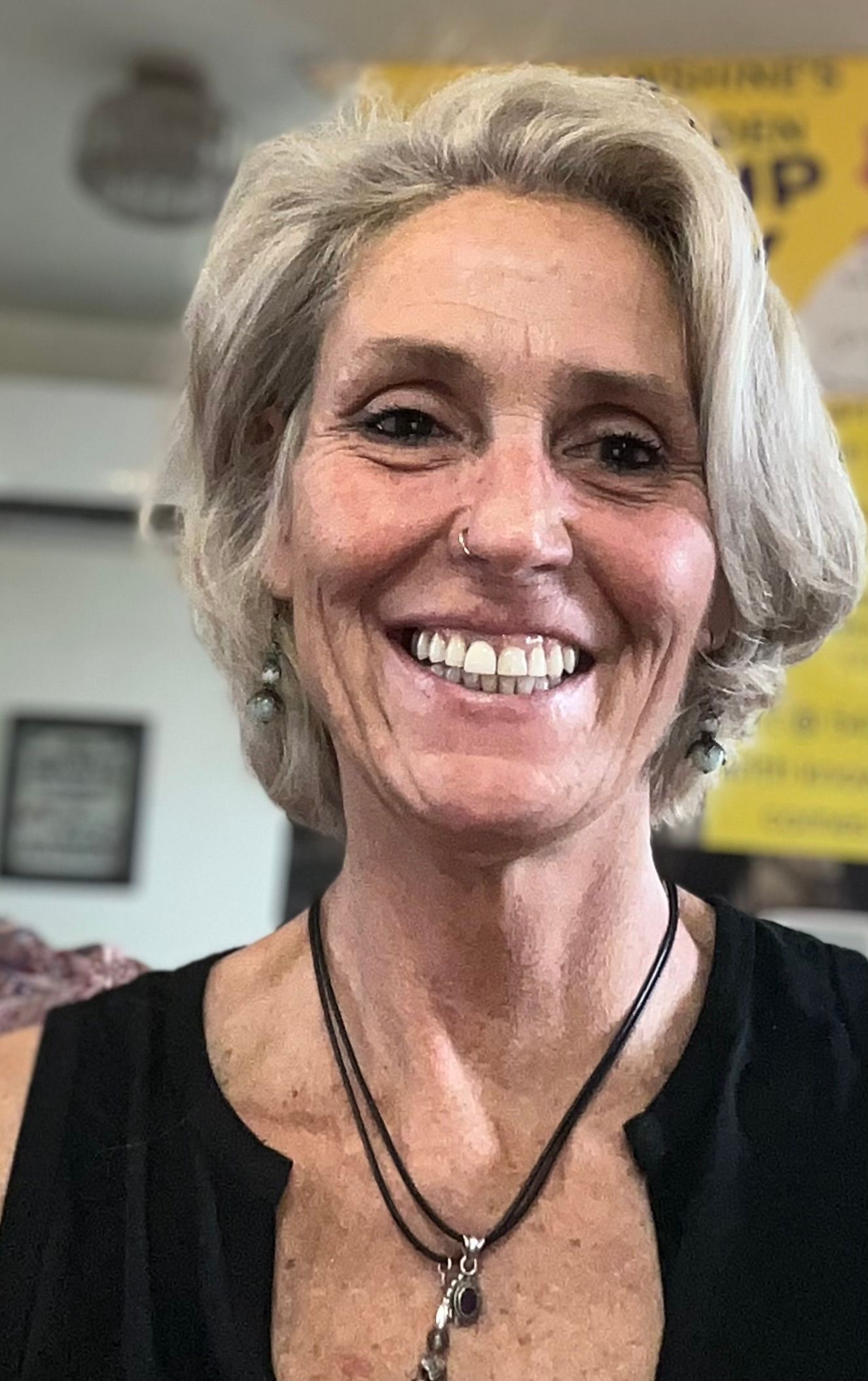 A woman wearing a nose ring and a necklace is smiling for the camera.