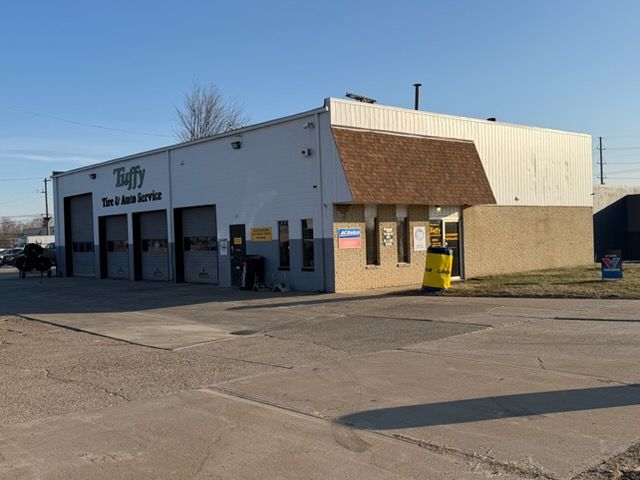 Exterior of Tuffy Tire & Auto Service building with three garage doors and a brown roofed entrance.