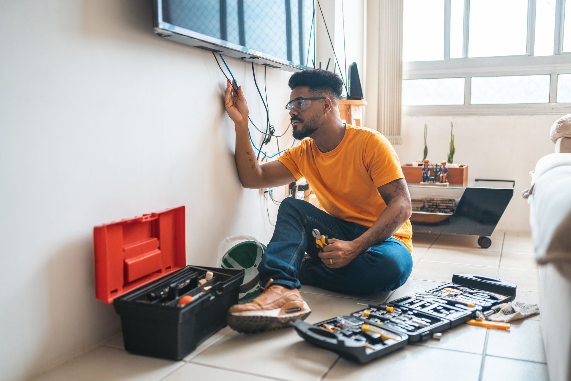 Electrician working with a flat tv’s screen cables at a cient’s home. Electrician working with a flat tv’s screen cables at a cient’s home.