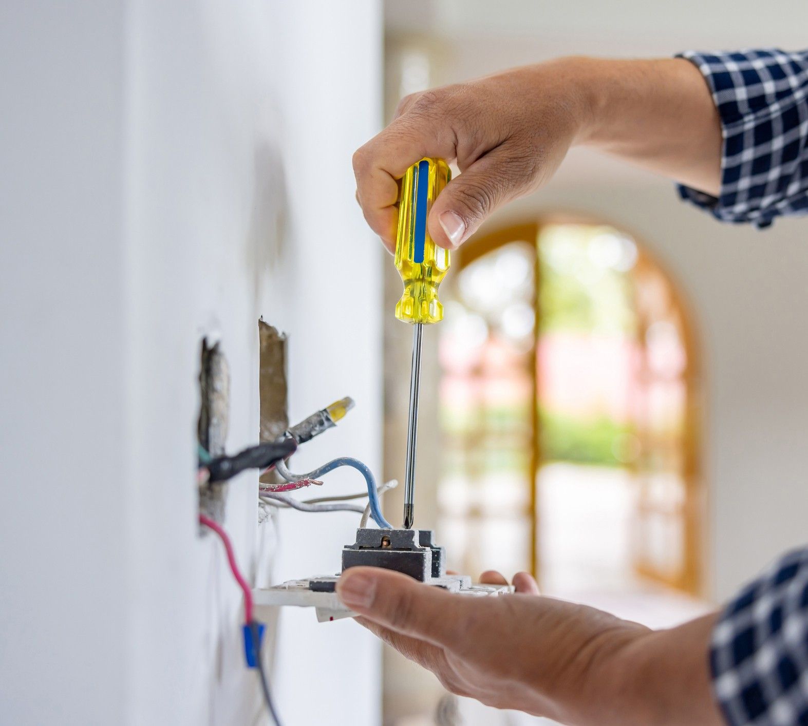 Electrician fixing or installing an outlet inside a house.