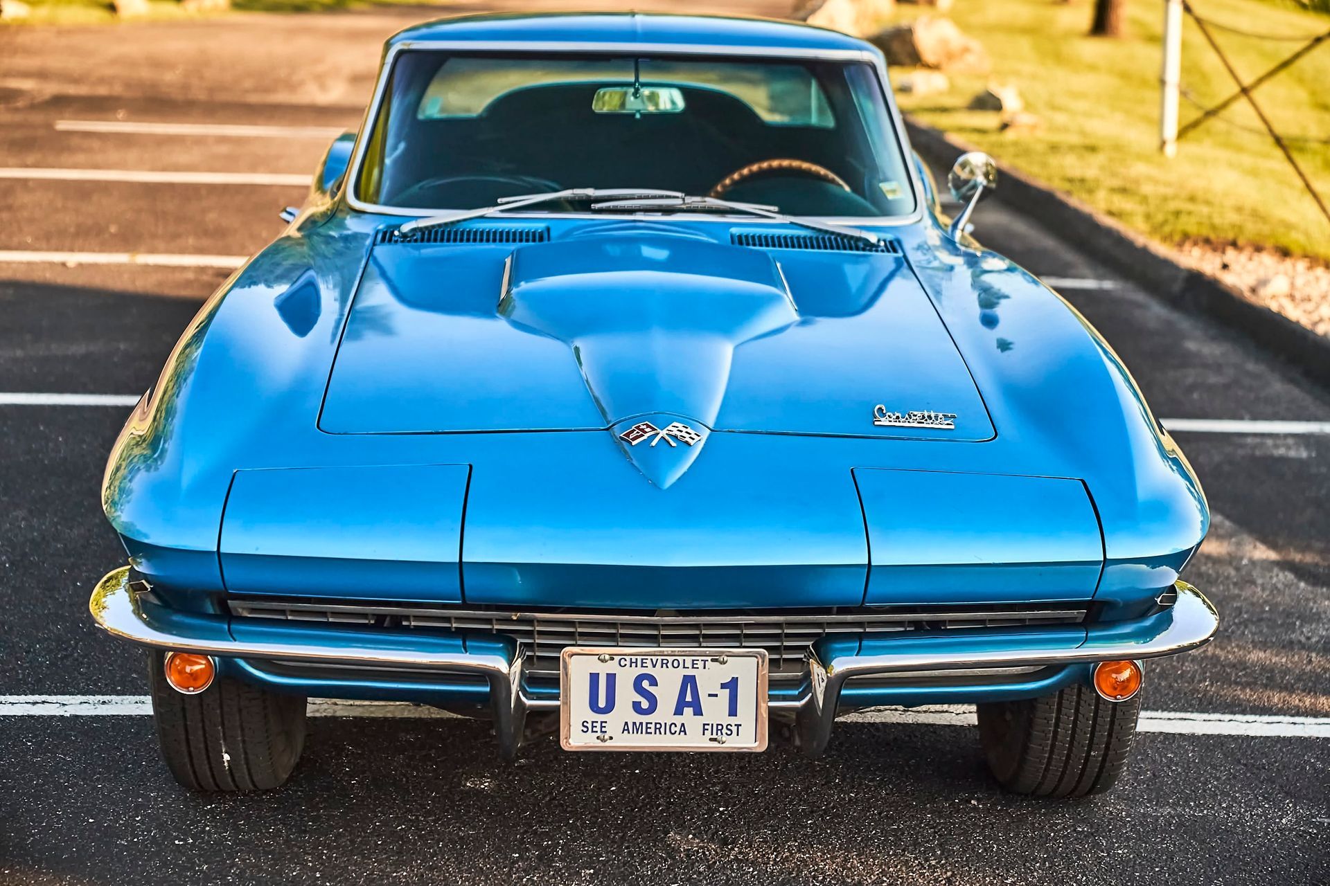 Blue classic Chevrolet Corvette sports car, parked outdoors, facing the viewer. A license plate reads