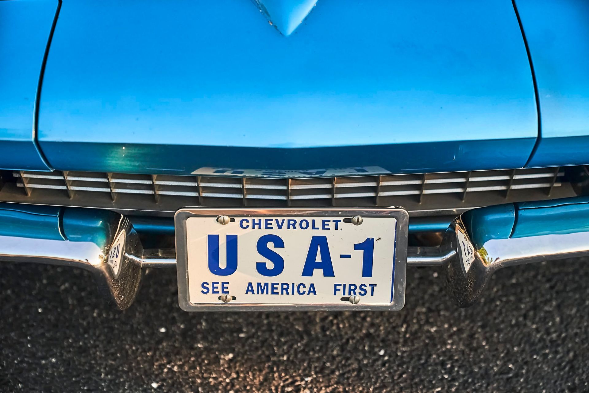 Close-up of a vintage blue Chevrolet car's front with a license plate that reads