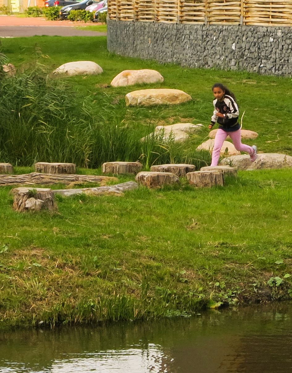 Een vrouw loopt over rotsen langs een waterpartij.