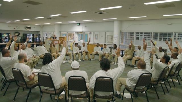 People in a circle raising hands in a meeting, indoors. Copyright 
