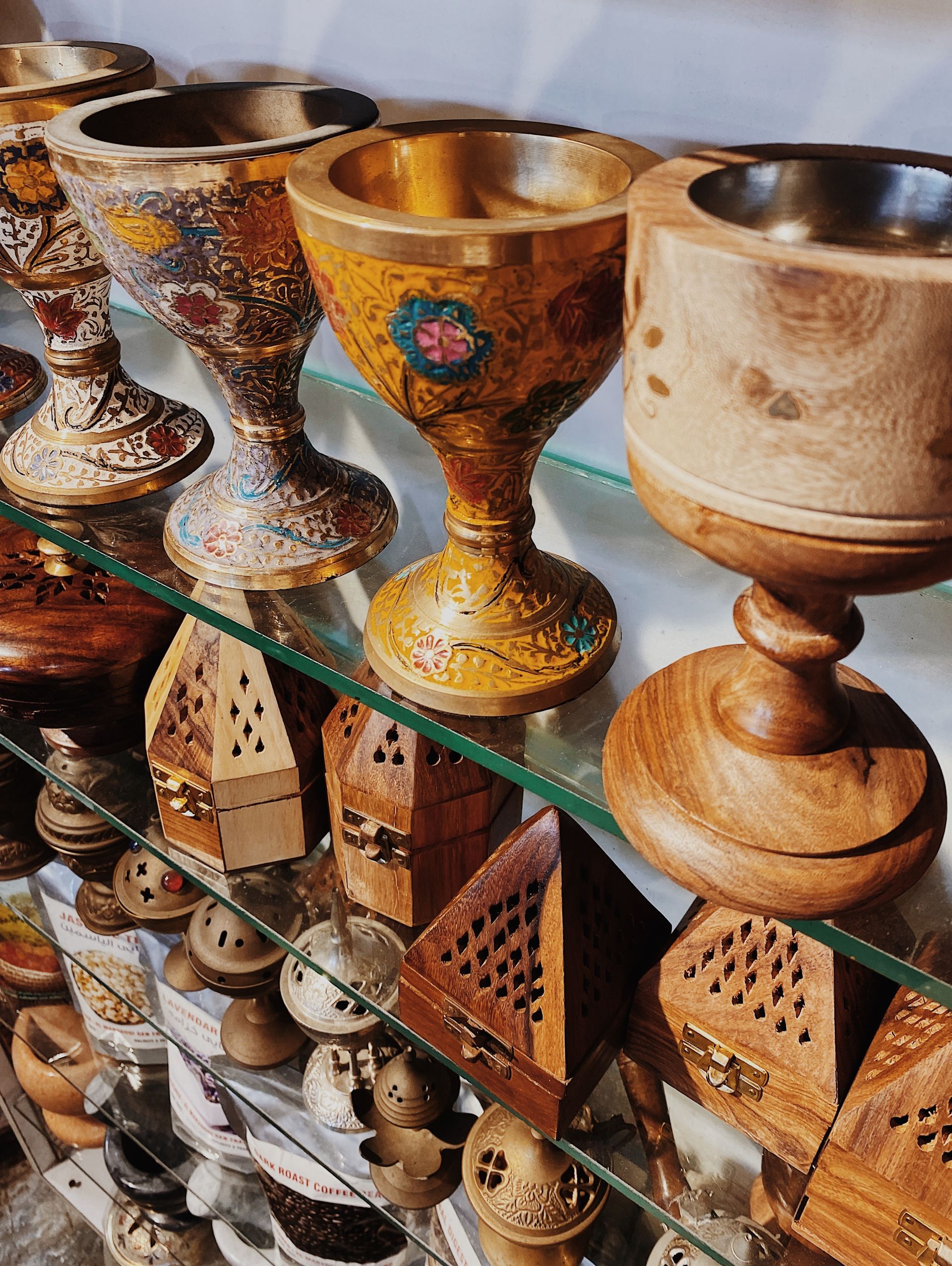 A glass shelf filled with a variety of wooden and metal objects.