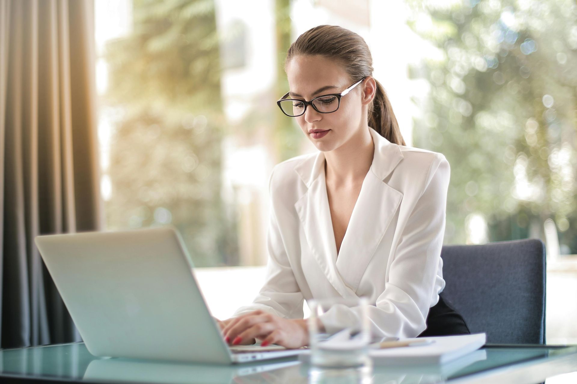 A woman is sitting at a desk using a laptop computer.