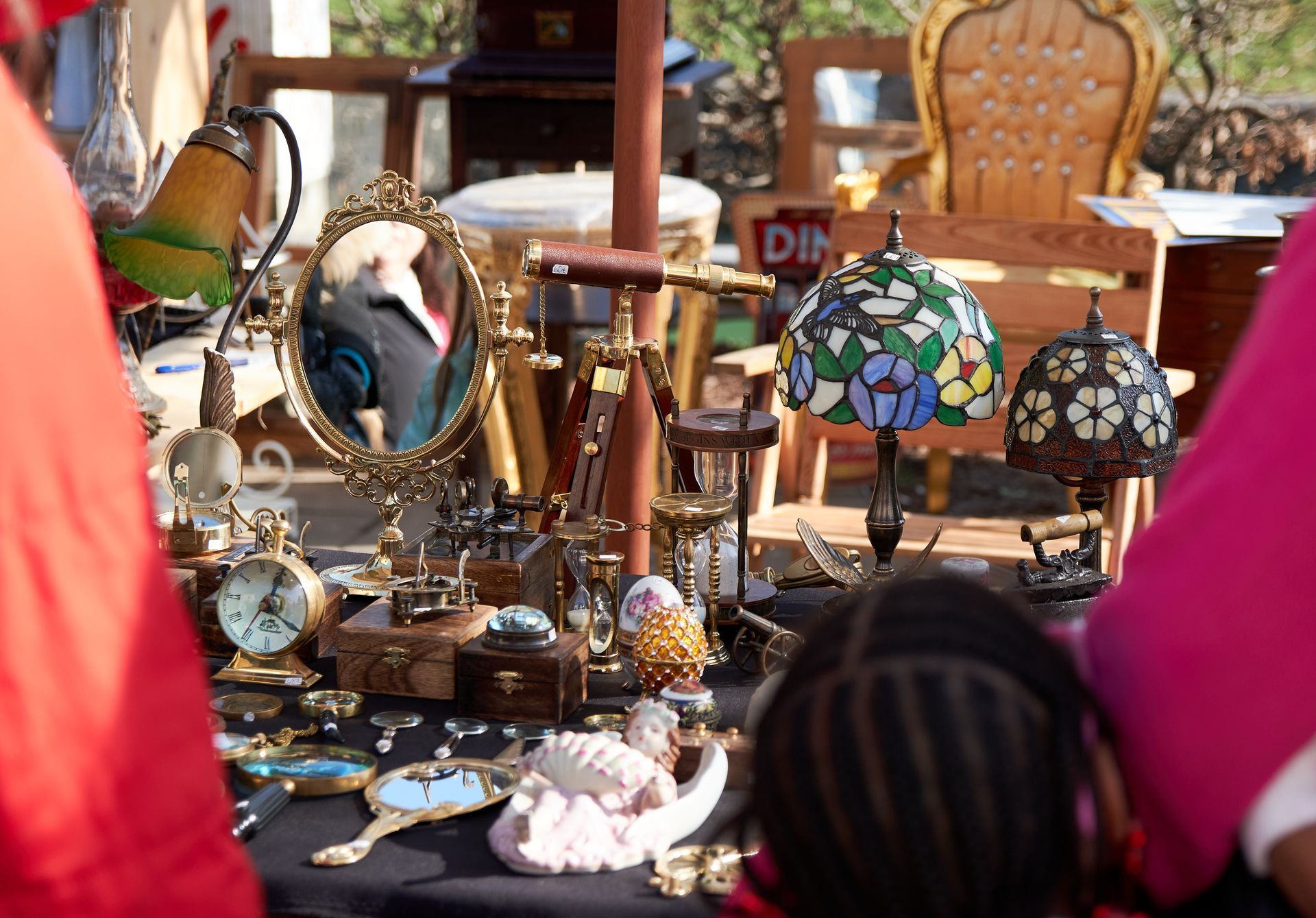 A group of people are looking at a table full of antique items